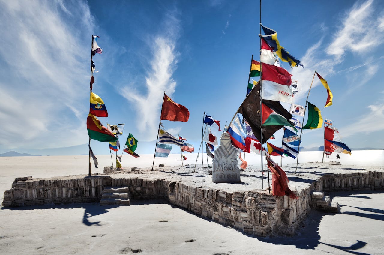 Vibrant international flags flying at Salar de Uyuni against a clear blue sky.